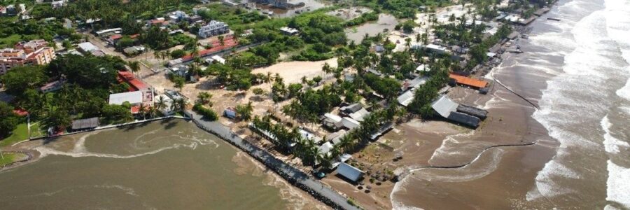 Aerial view of a tropical coastal community beside eroding muddy shores