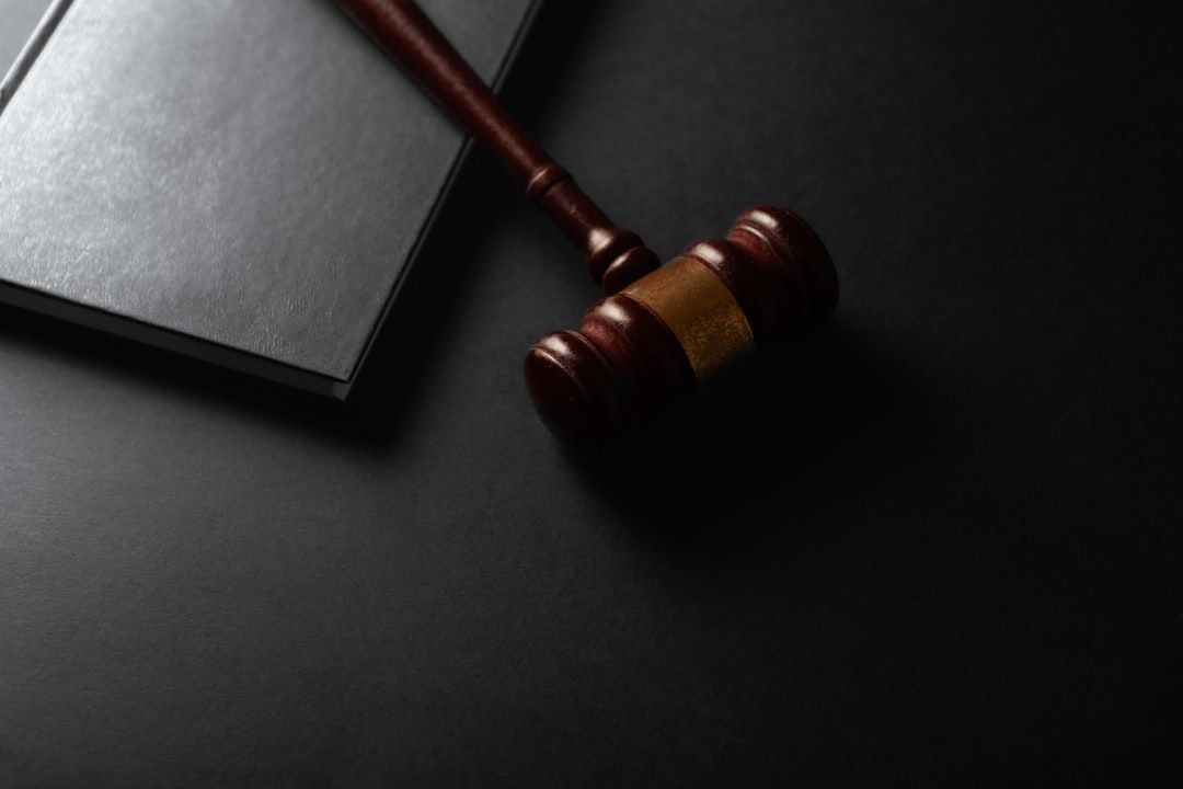 Wooden courtroom gavel resting beside a closed dark document folder