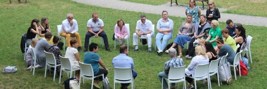Community members seated in a circle outdoors during a group meeting